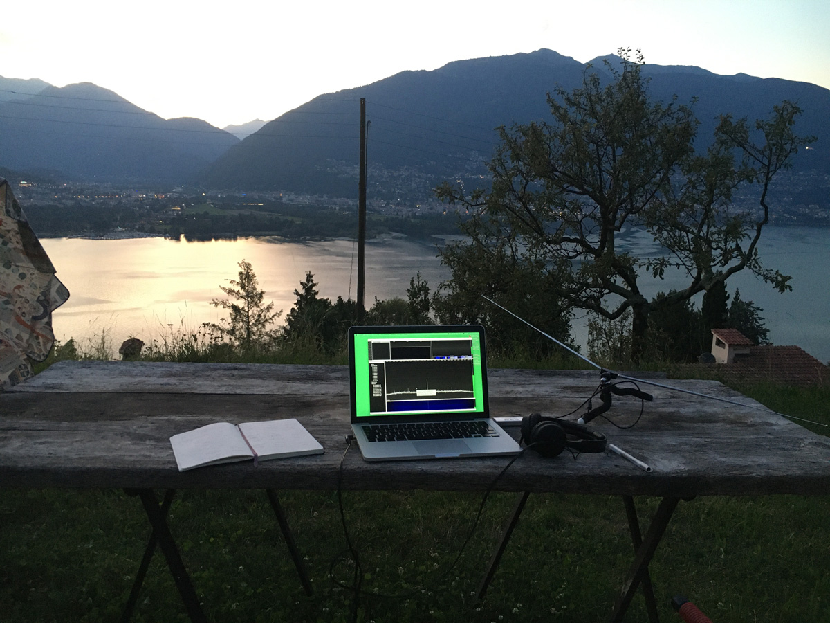 a table with a laptop and antenna on it looking over a lake and mountains